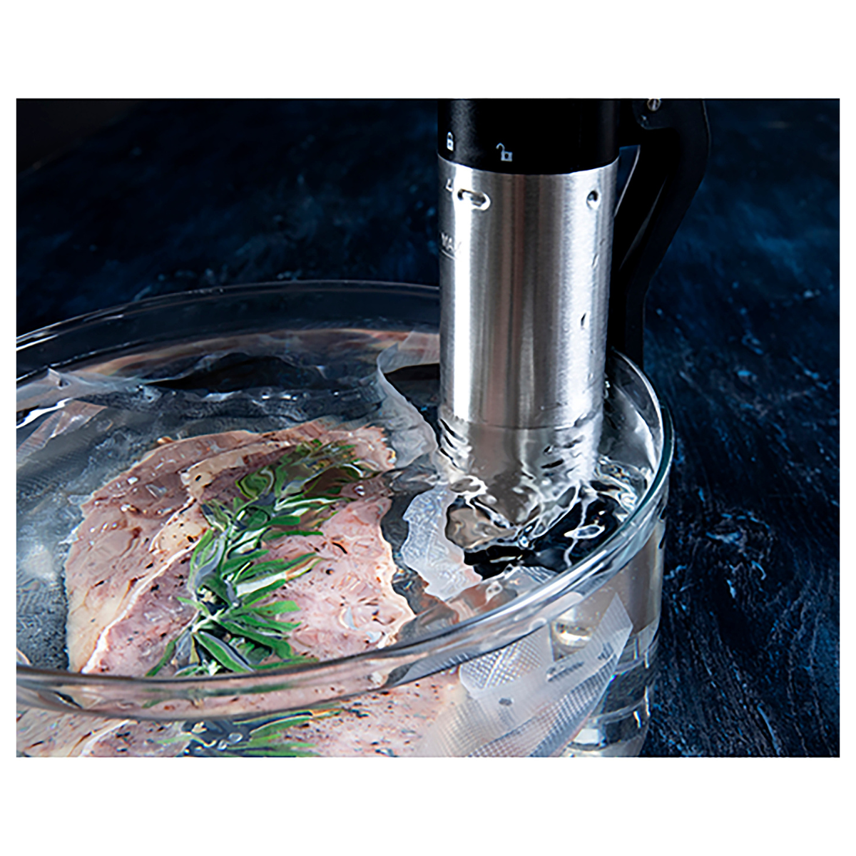 Urządzenie sous vide znajduje się w misce z wodą, mięsem i ziołami.