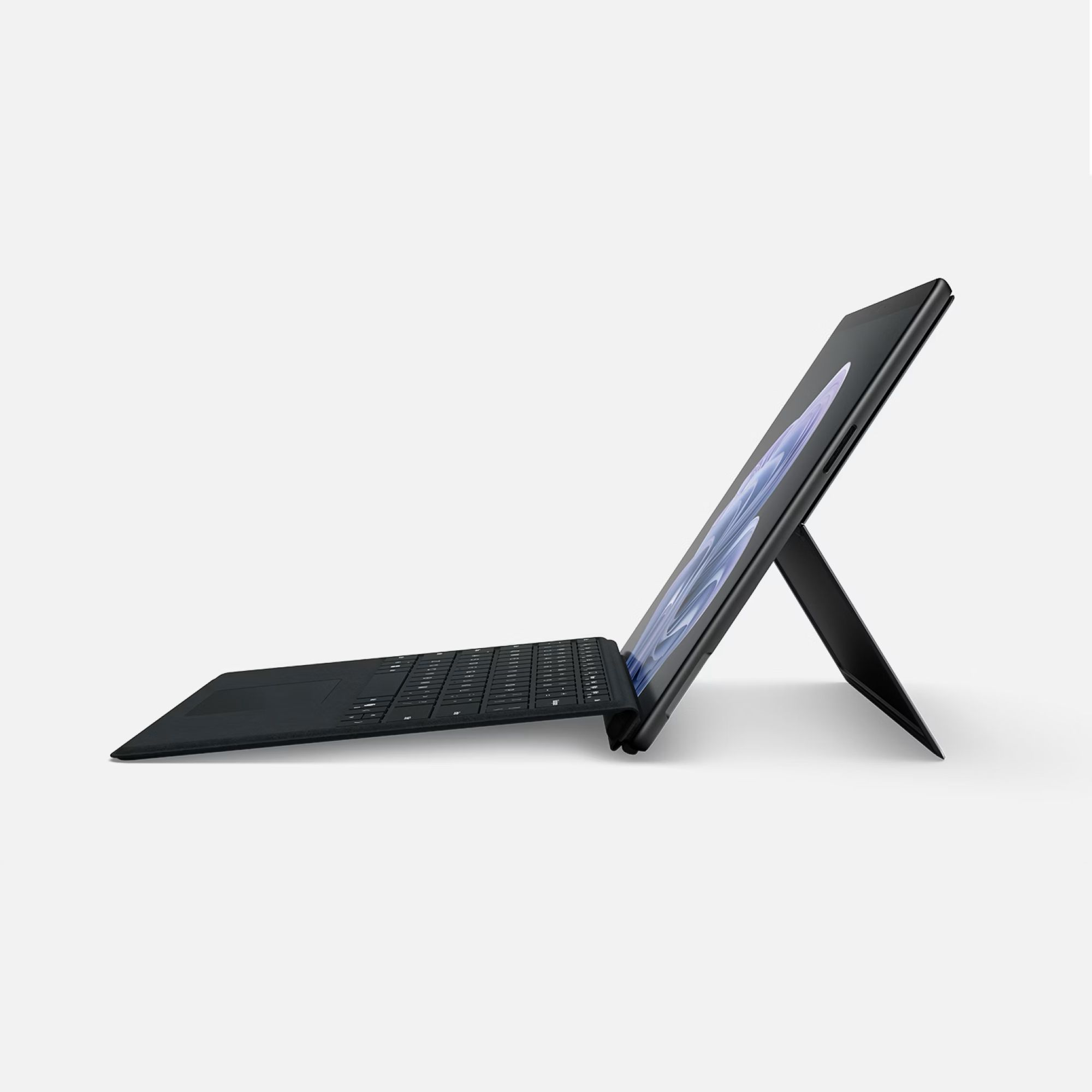 Un tablet nero con tastiera e supporto, visto di lato su sfondo bianco.