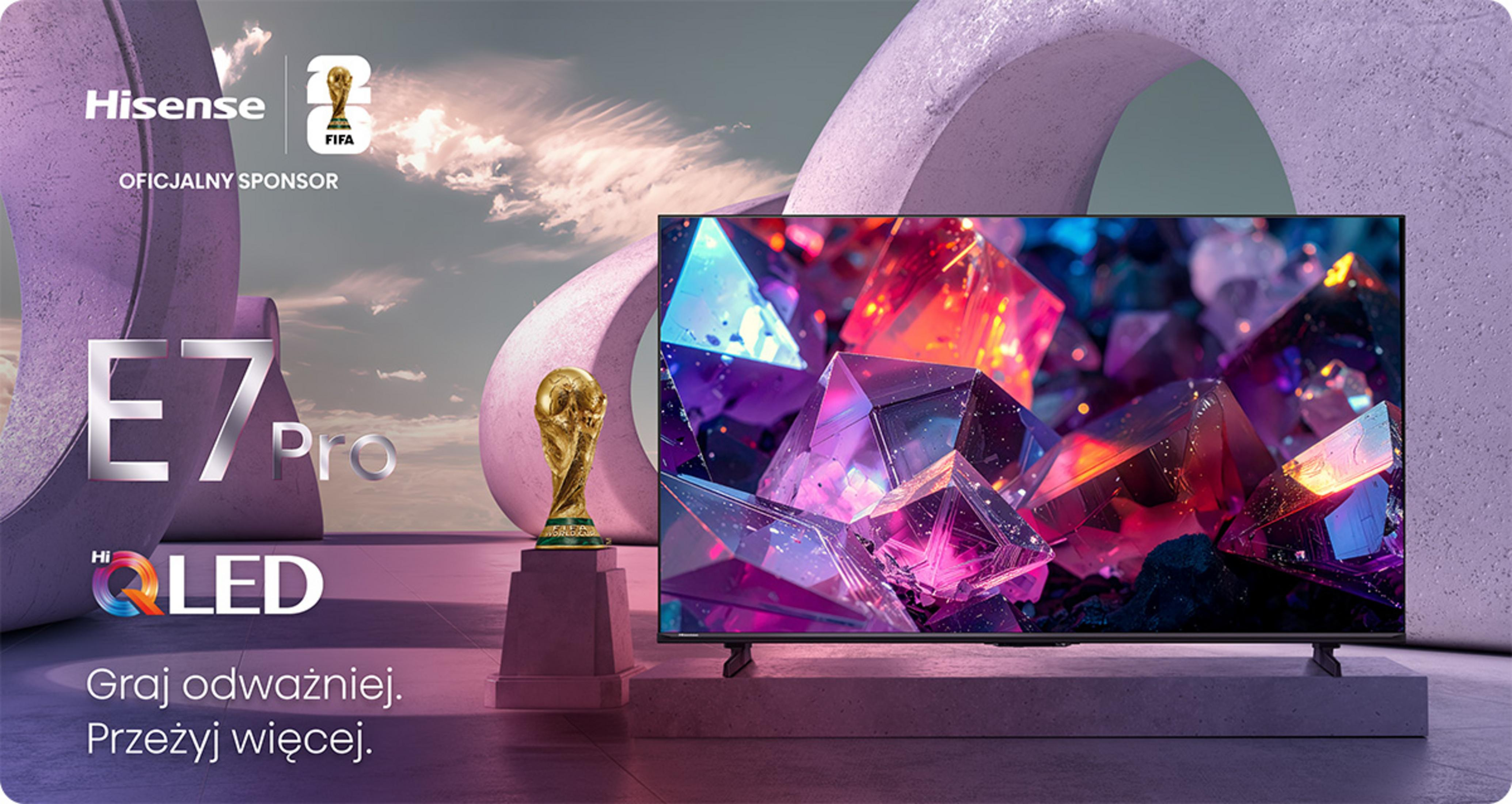 TV Hisense E7 Pro QLED accanto a un trofeo FIFA, inserito in un paesaggio architettonico viola con nuvole.