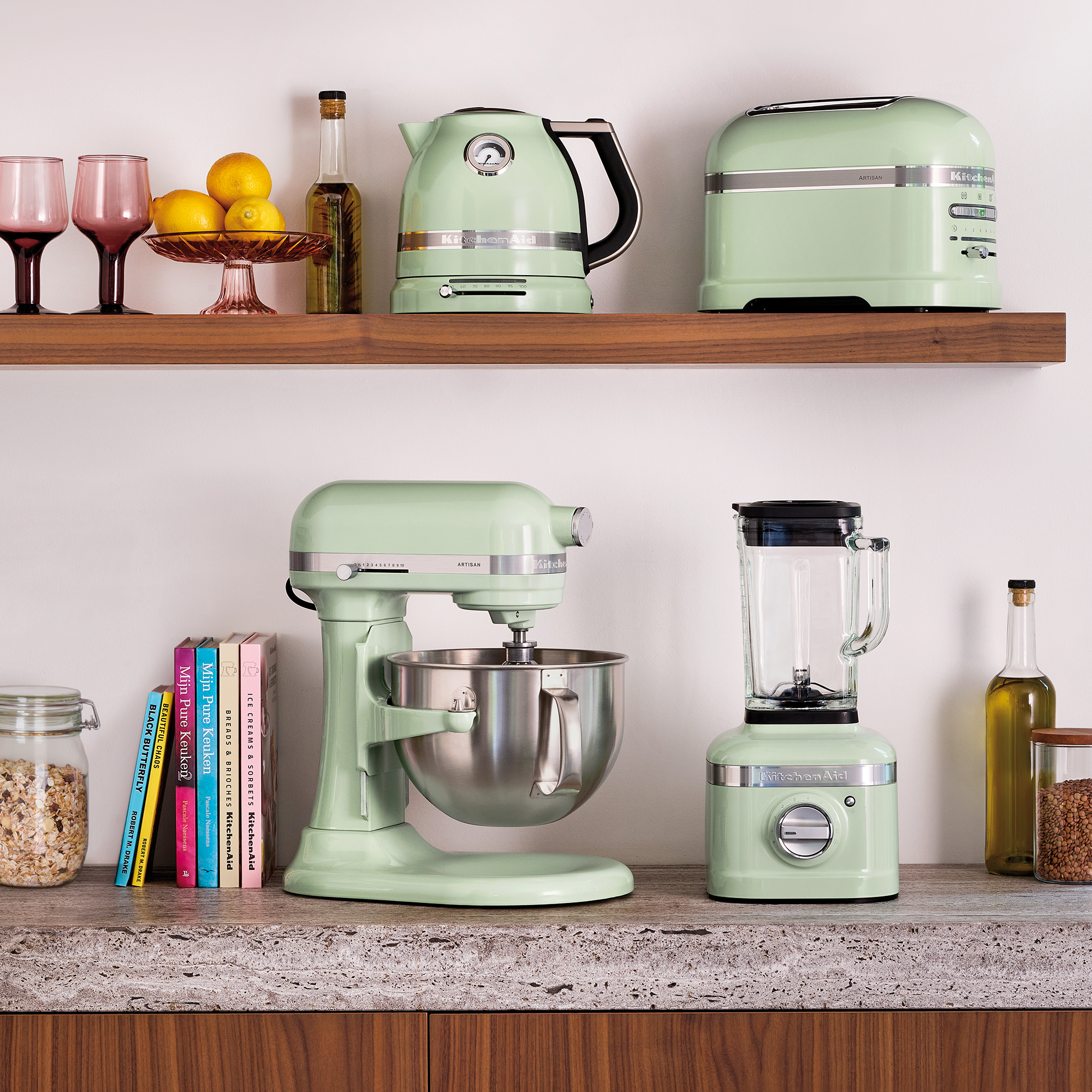 Pastellgrüne Küchengeräte wie Mixer, Toaster und Kaffeekanne auf Holzböden.