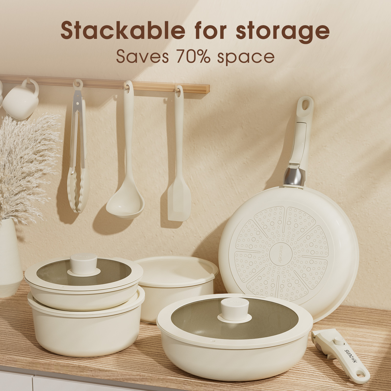 Batterie de cuisine beige avec casseroles empilables, poêles et ustensiles suspendus.