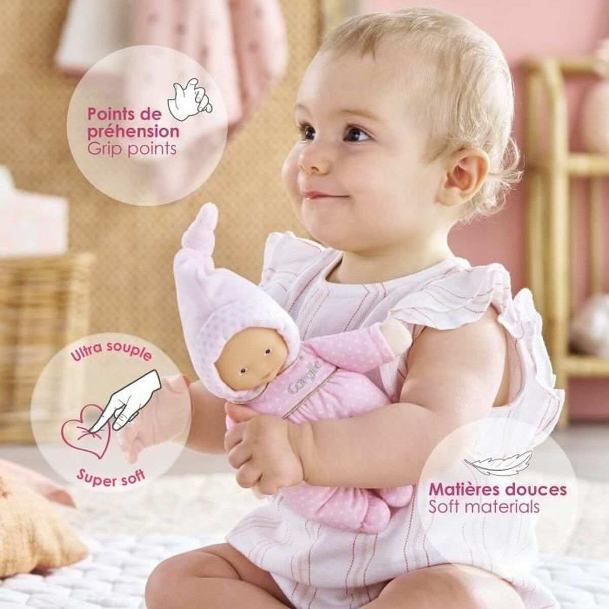 Ein Baby in weißer Kleidung hält eine weiche rosa Puppe, umgeben von erklärenden Produktmerkmalen.