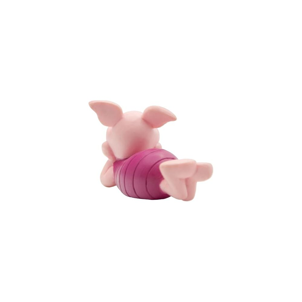 Eine kleine rosa Ferkel-Figur mit gestreiftem lila Shirt liegt auf dem Bauch vor weißem Hintergrund.