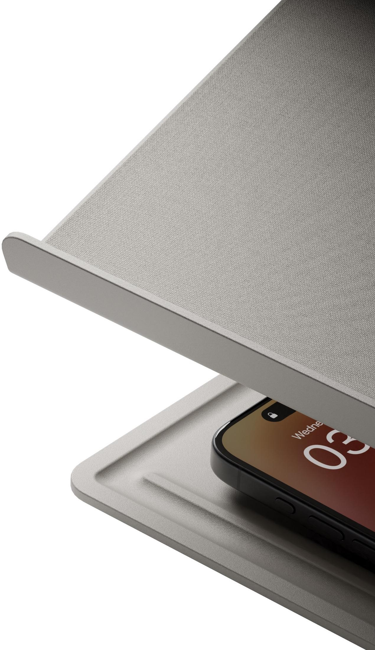 Ein grauer Laptopständer auf einer grauen Oberfläche mit einem sichtbaren Smartphone.