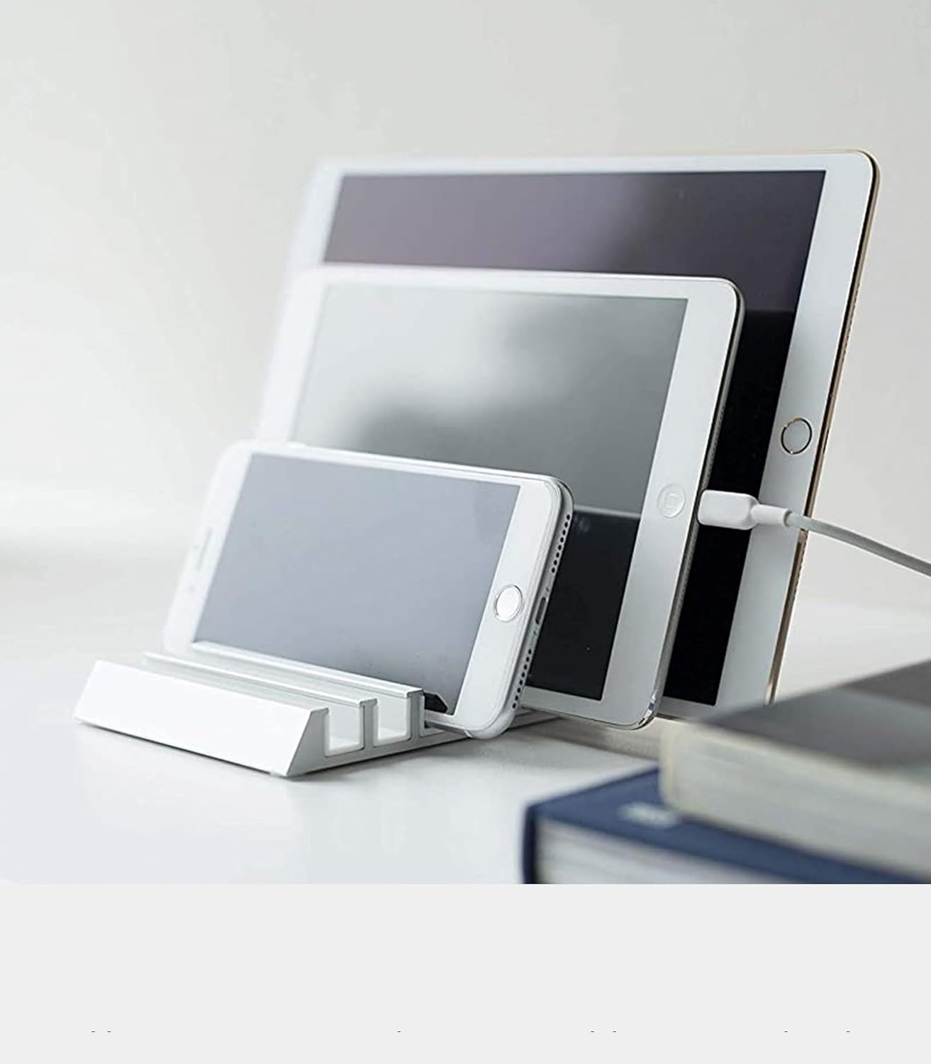 Biały metalowy stojak mieści smartfon i dwa tablety, z podłączonym kablem ładującym.