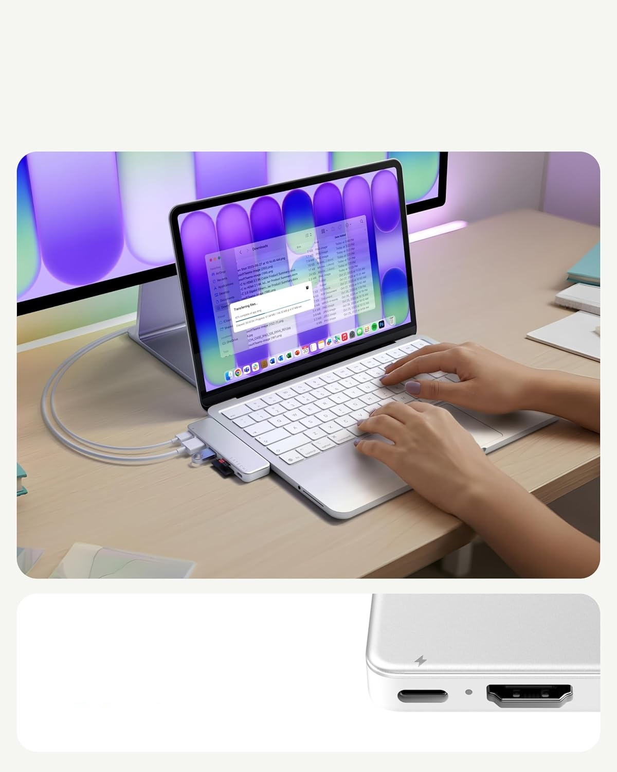 Ręce piszące na srebrnym tablecie z hubem, podłączonym do monitora na drewnianym biurku.