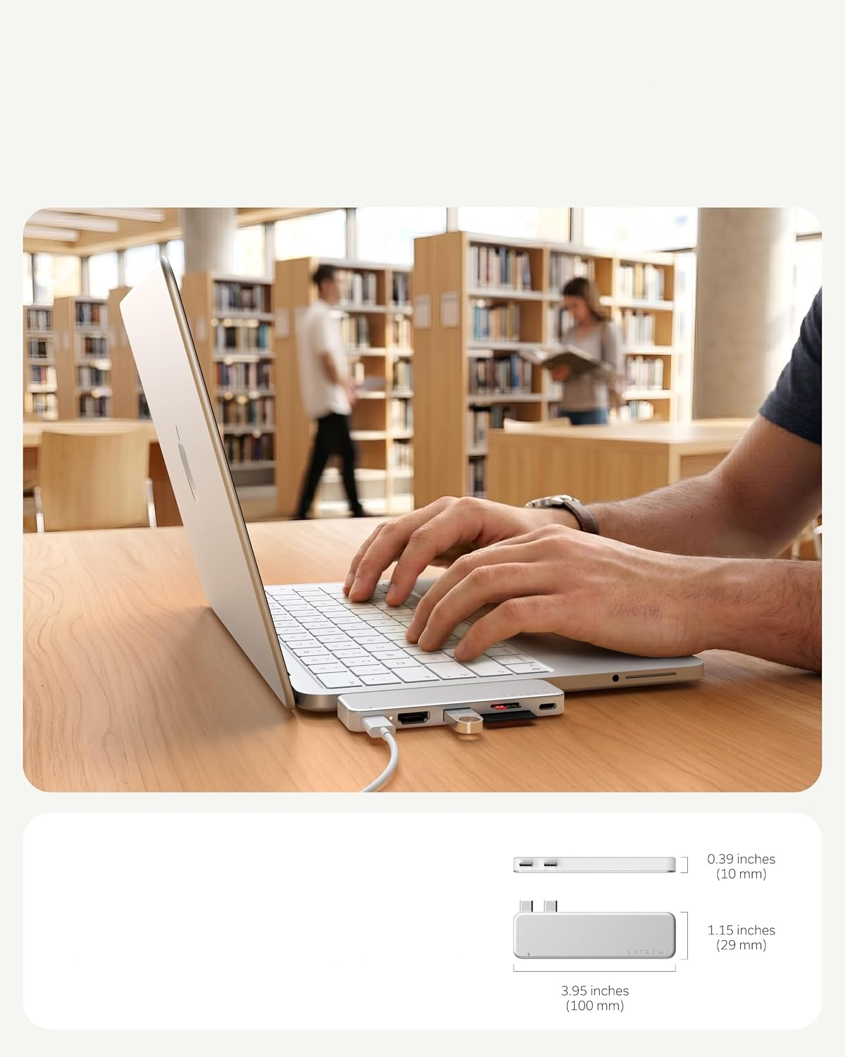 Osoba pisze na laptopie z hubem USB na drewnianym biurku w bibliotece.