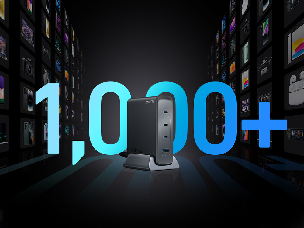 Ładowarka Anker na pierwszym planie z niebieskim tekstem "1,000+" i ścianami małych świecących ekranów w tle.