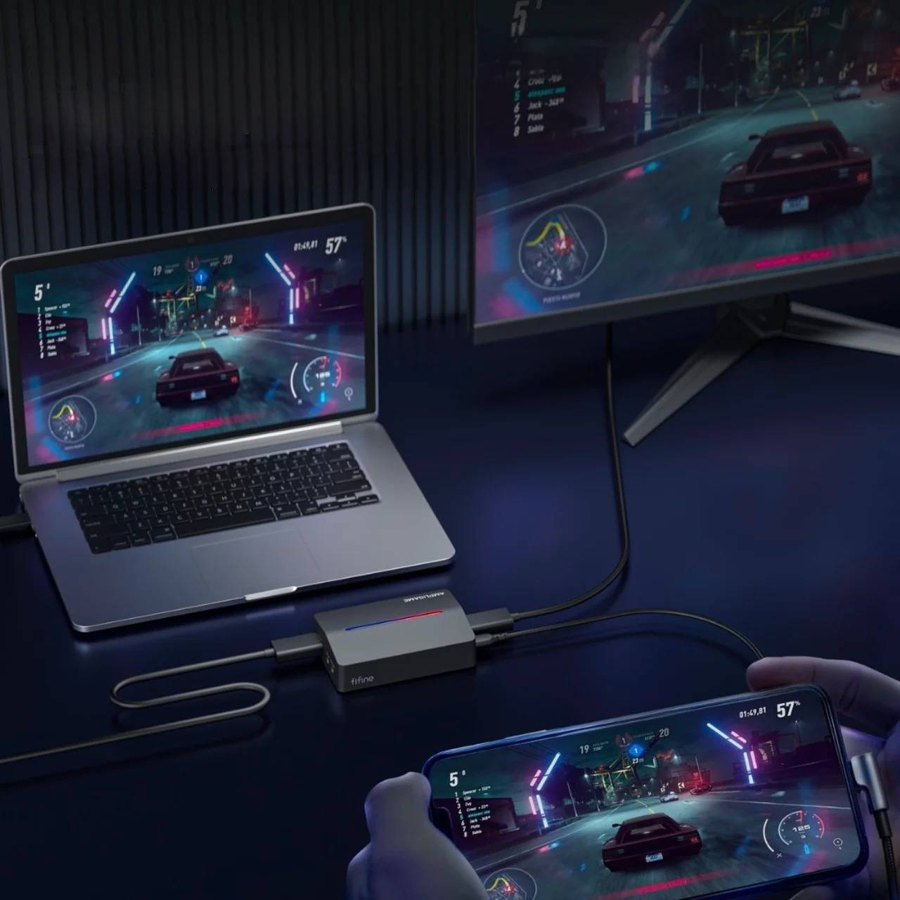 Smartfon, laptop i monitor połączone stacją dokującą wyświetlają grę wyścigową.