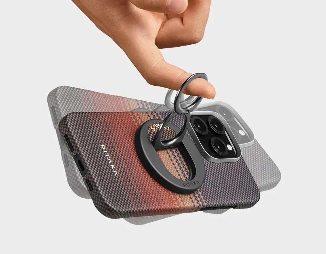 Ręka unosi metalową podstawkę z pierścieniem z tyłu etui na telefon.