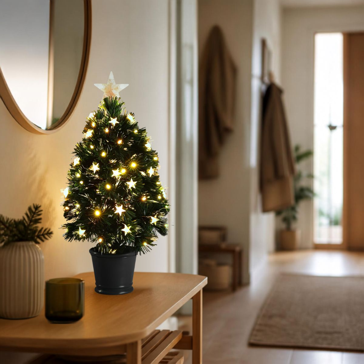 Kleiner, beleuchteter Weihnachtsbaum im Topf auf einem Holztisch in einem hellen Flur.