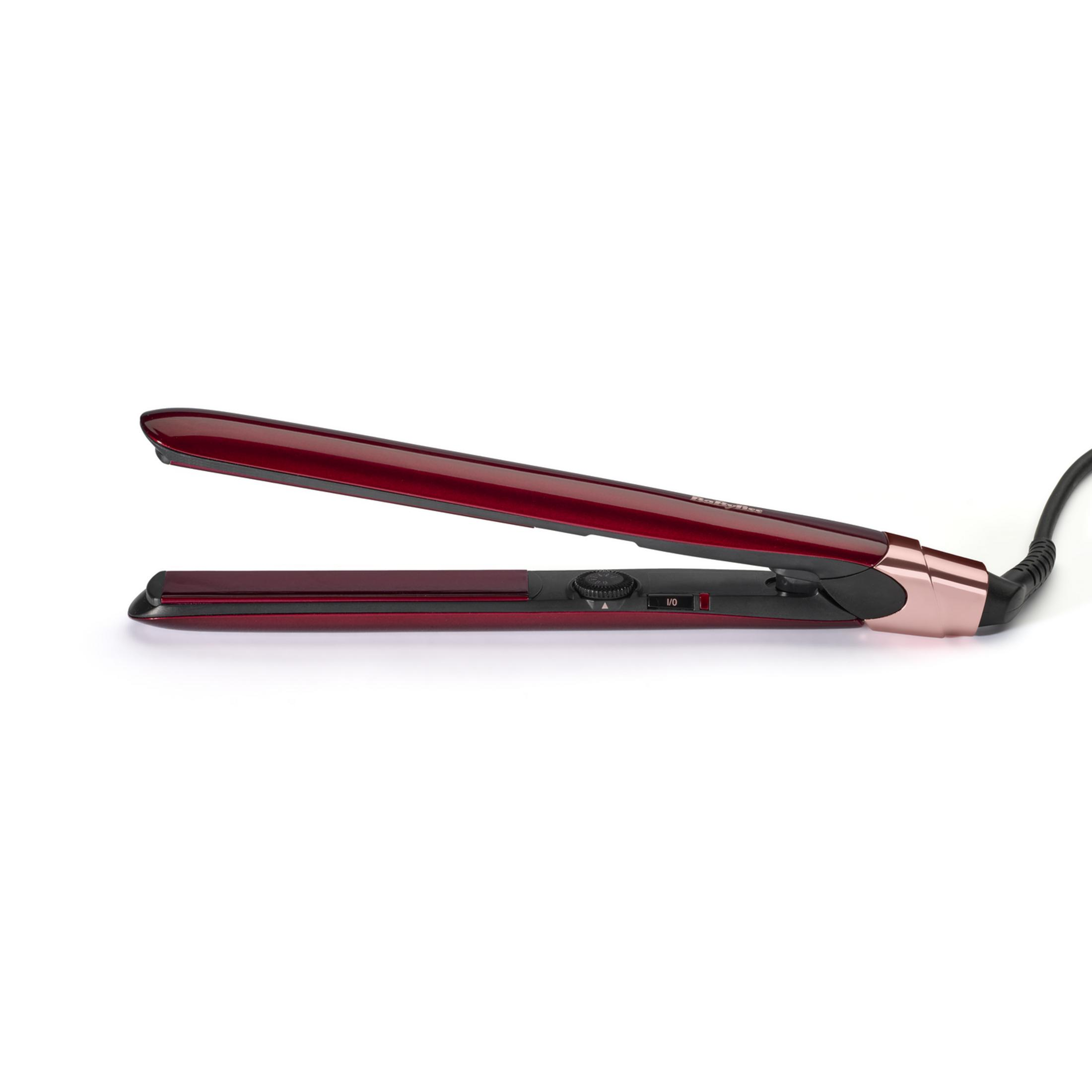Una piastra per capelli rossa e nera con dettagli in oro rosa si trova orizzontalmente su sfondo bianco.