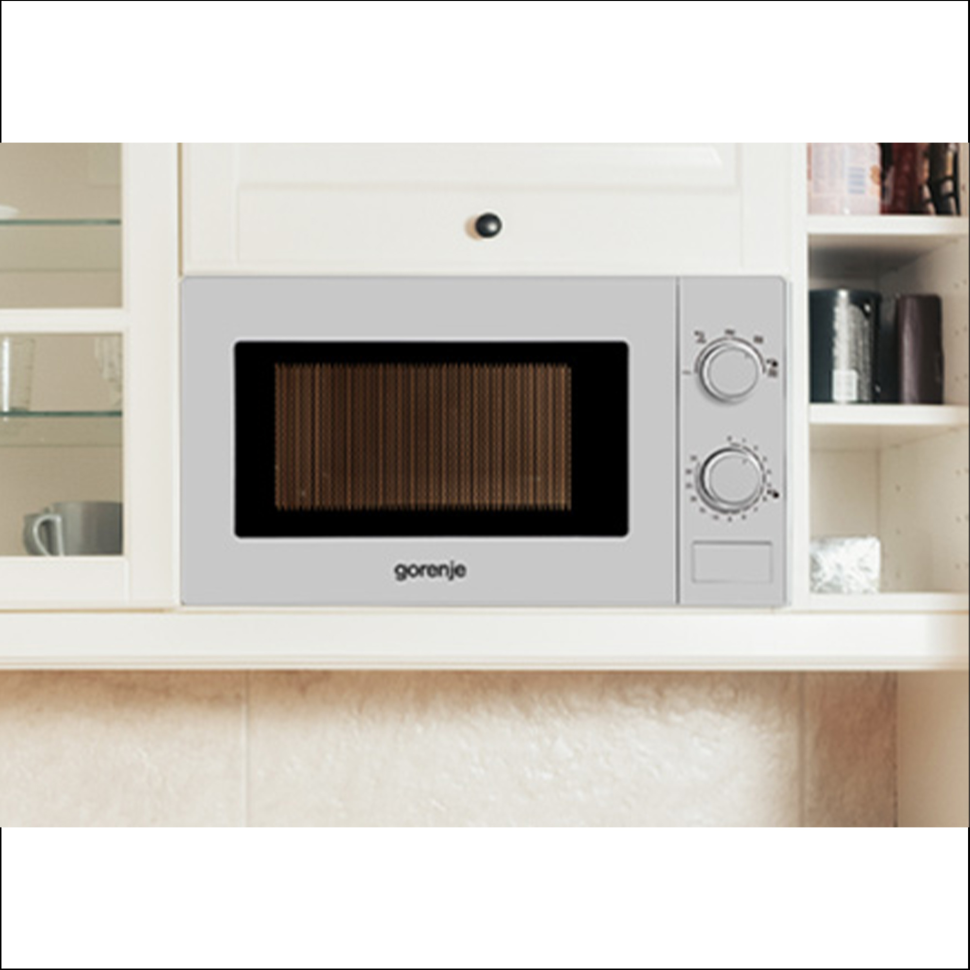 Eine graue Gorenje-Mikrowelle ist eingebaut in eine weiße Küchenzeile mit Regalen und Schränken.