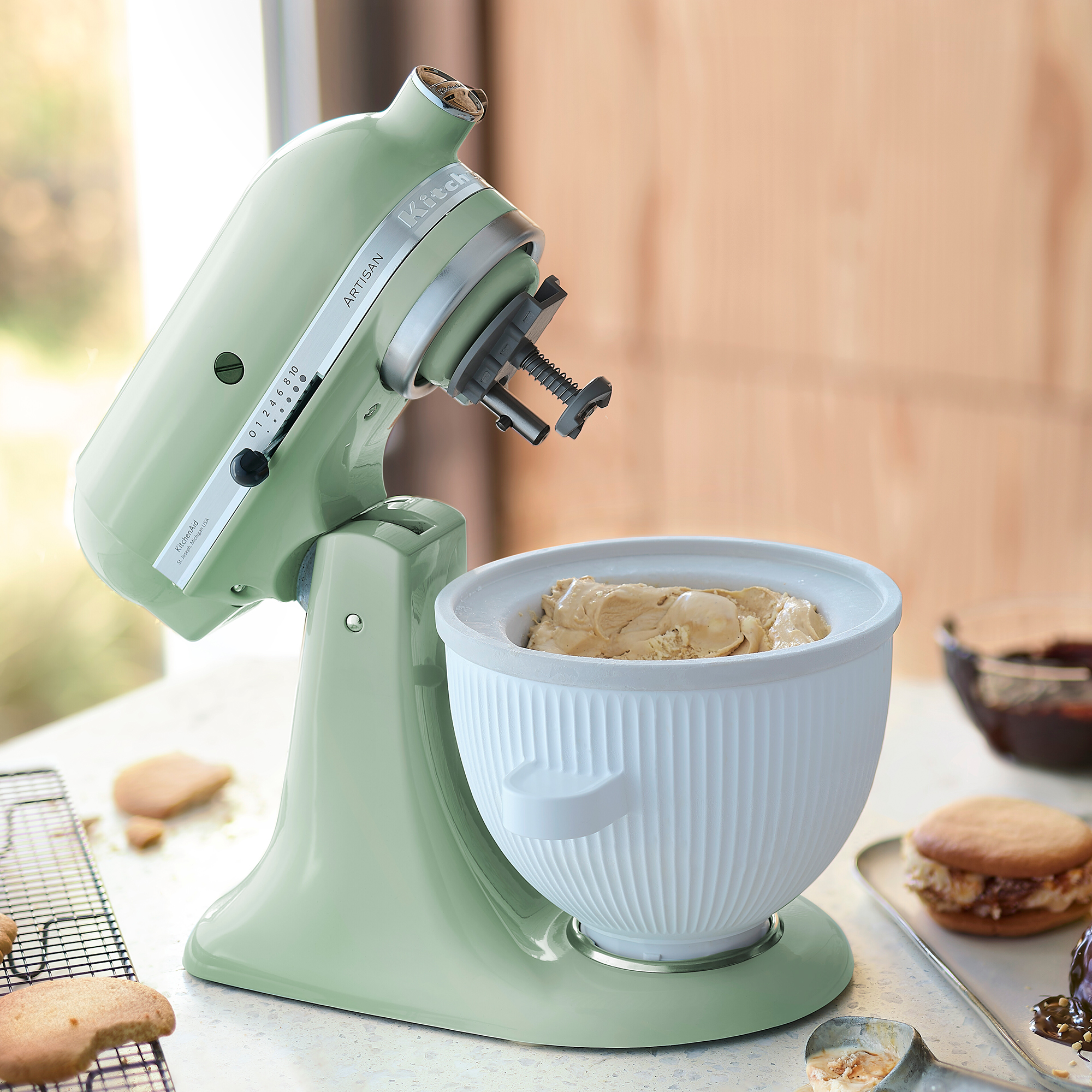 Un'impastatrice KitchenAid verde pistacchio con una ciotola bianca piena di gelato su un bancone.