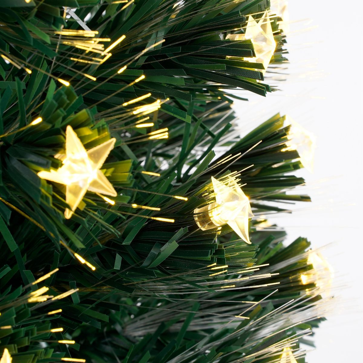 Close-up of an artificial Christmas tree with bright glowing star lights and fiber optics.
