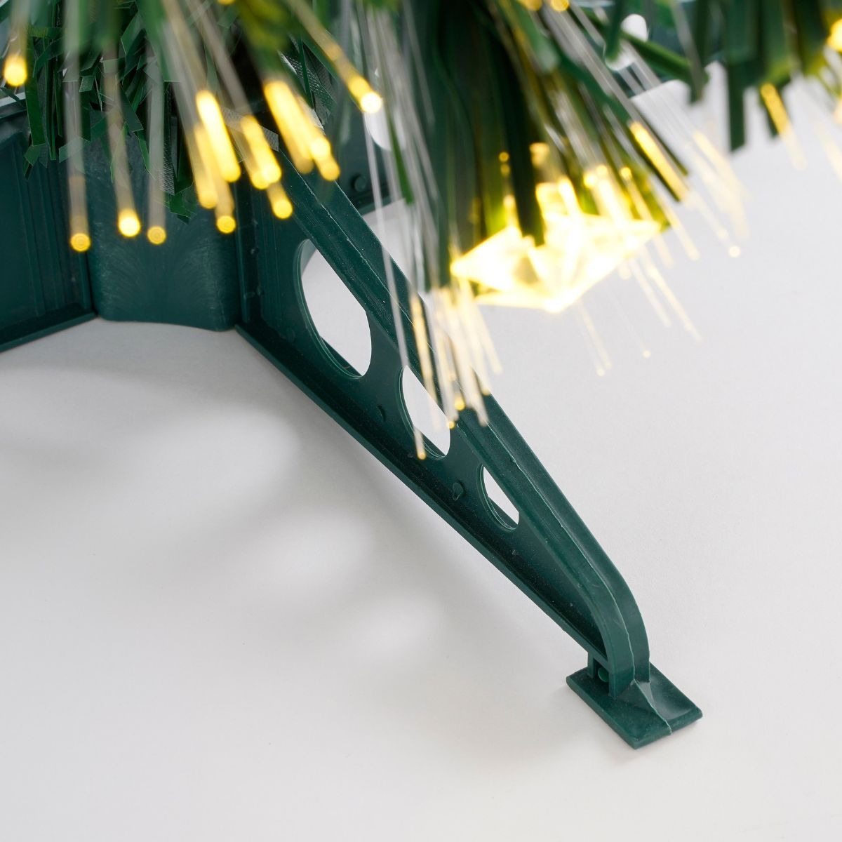 A green plastic stand supports an artificial Christmas tree with fiber optic lights.