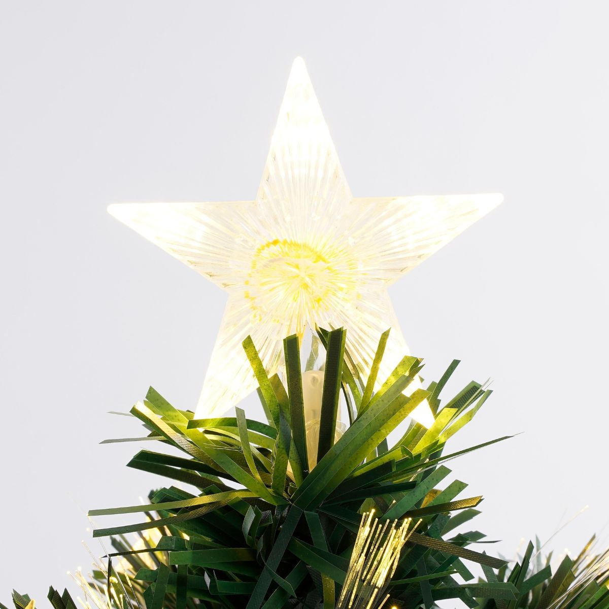 A glowing white star sits atop an artificial green Christmas tree with fiber optic needles.
