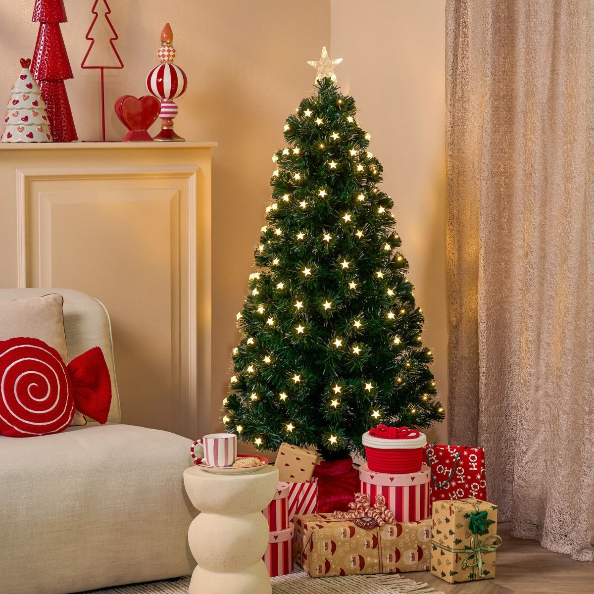 A lit Christmas tree with star lights stands beside a sofa and wrapped gifts in a warmly lit room.