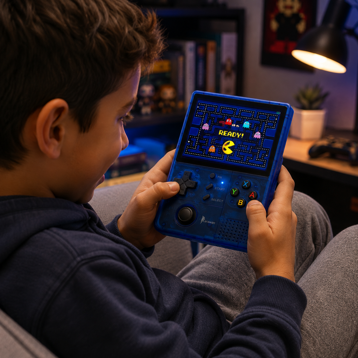 Un niño en una habitación oscura juega a Pac-Man en una consola portátil azul.
