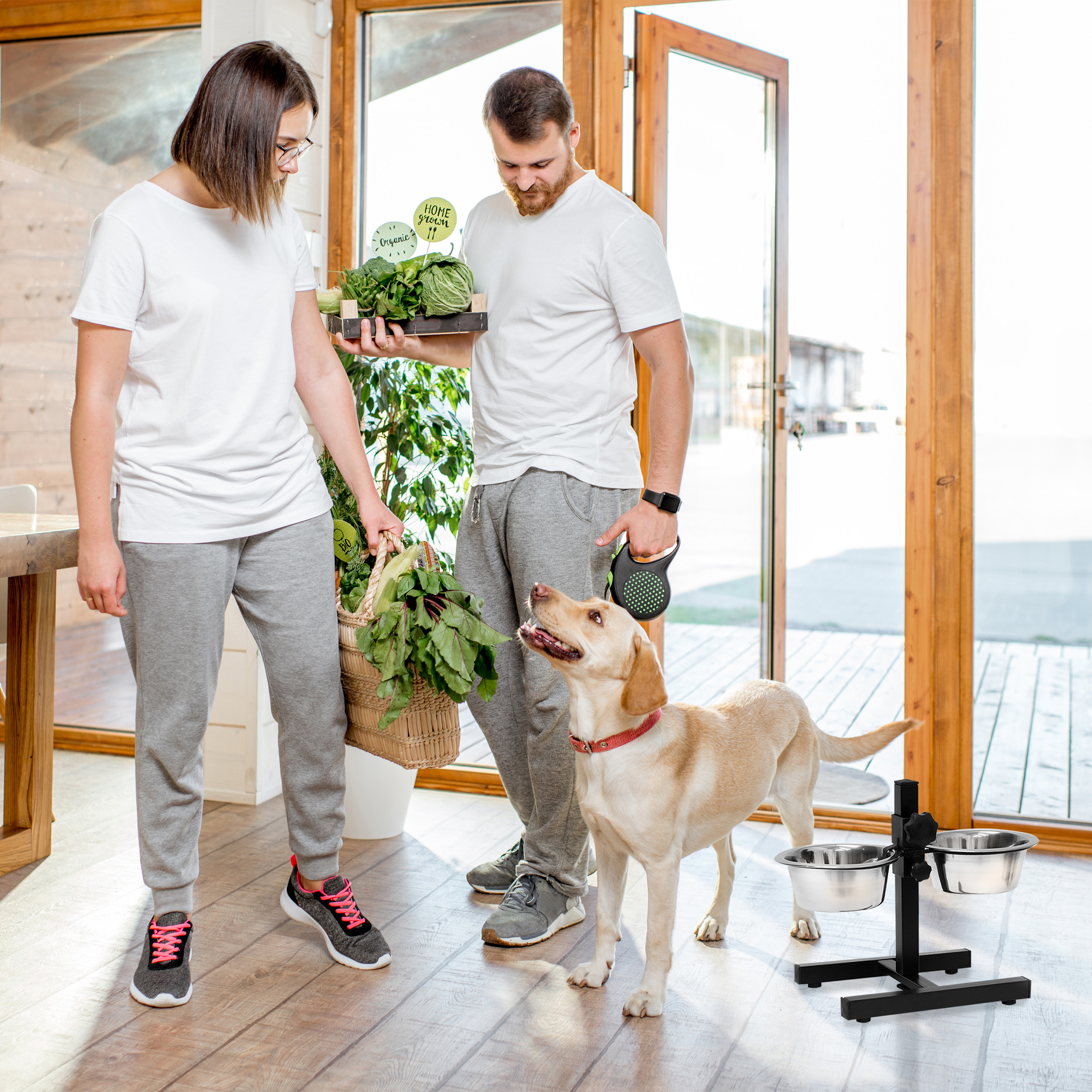 Ein Paar mit frischem Gemüse und ein Hund in einem hellen Raum.