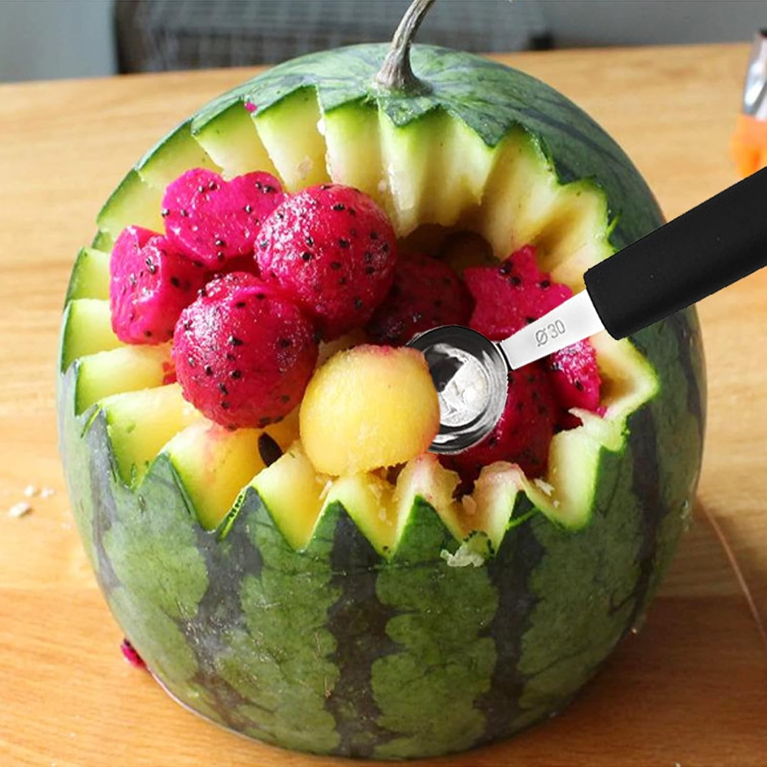 Eine kunstvoll geschnitzte Wassermelone gefüllt mit roten Drachenfruchtkugeln und einer Melonenkugel.