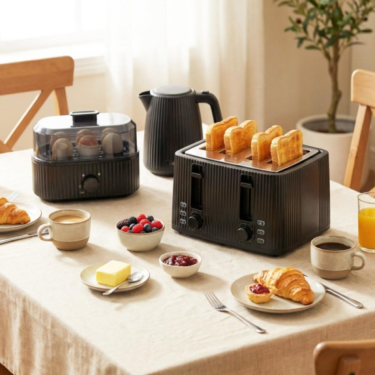 Ein Frühstückstisch zeigt einen schwarzen Toaster, Eierkocher, Wasserkocher, Kaffee, Croissants und Beeren.