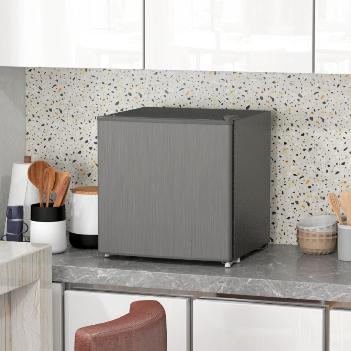 Ein dunkelgrauer Mini-Kühlschrank steht auf einer grauen Marmor-Küchenarbeitsplatte, flankiert von Utensilien und Gläsern.