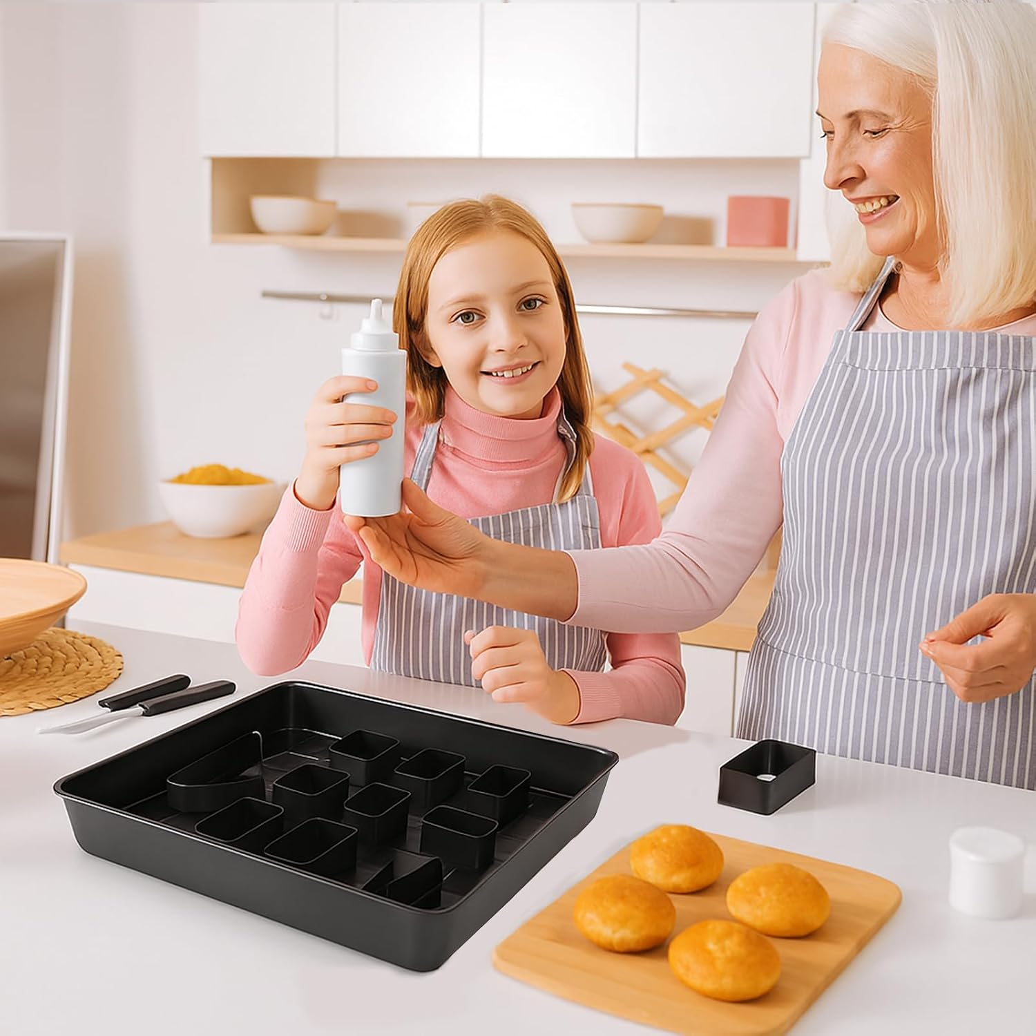 Eine Seniorin und ein Mädchen in Schürzen backen gemeinsam in einer hellen Küche und halten eine Saucenflasche.