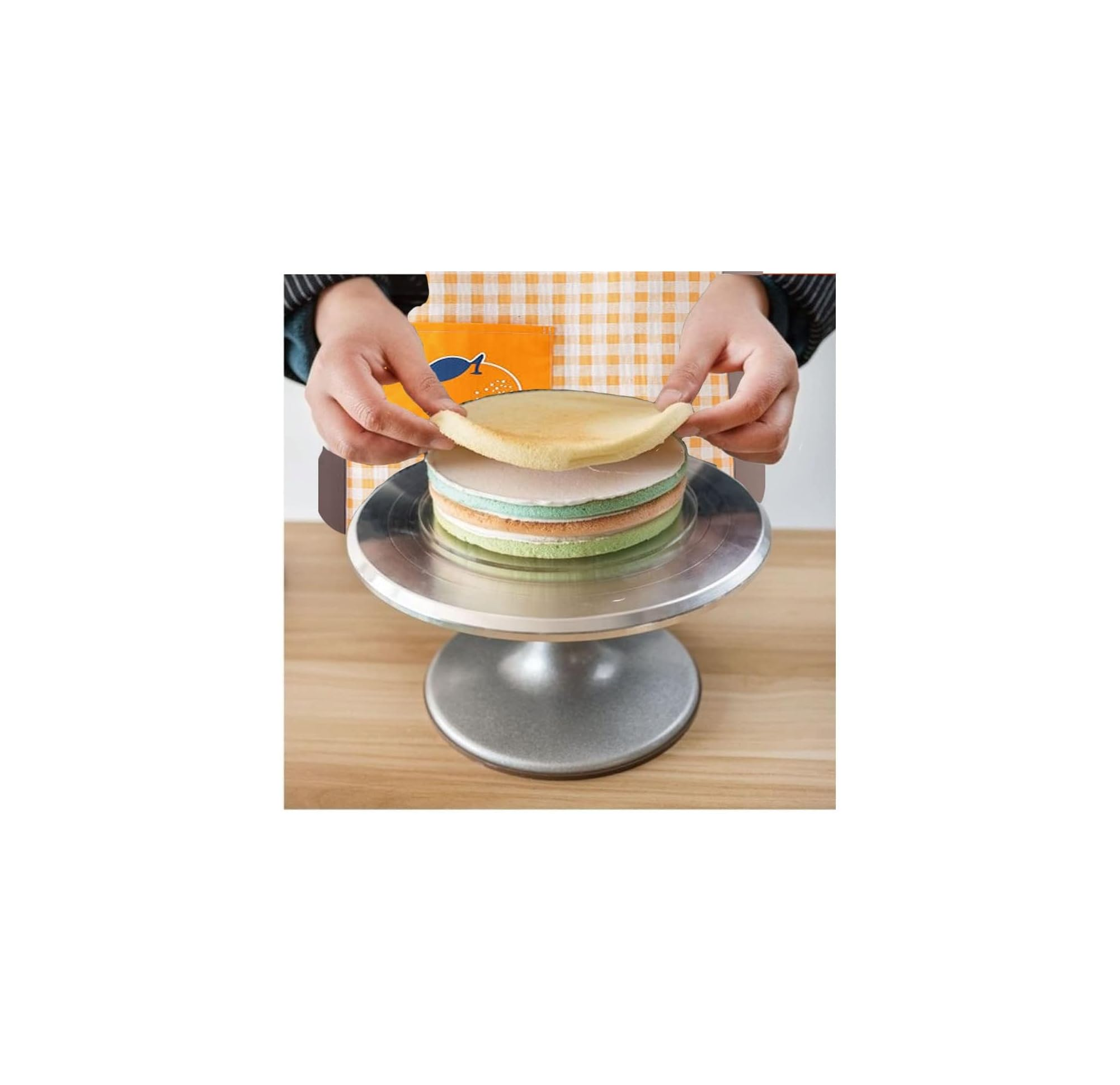 Hände platzieren einen dünnen Teigboden auf eine mehrfarbige Torte auf einer rotierenden Ständer.