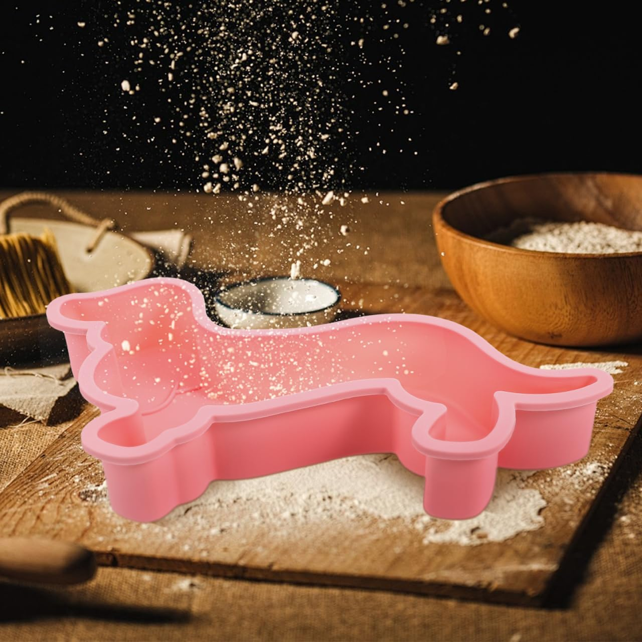 Eine pinke Dackel-Backform auf einem Holztisch, während Mehl darüberrieselt.