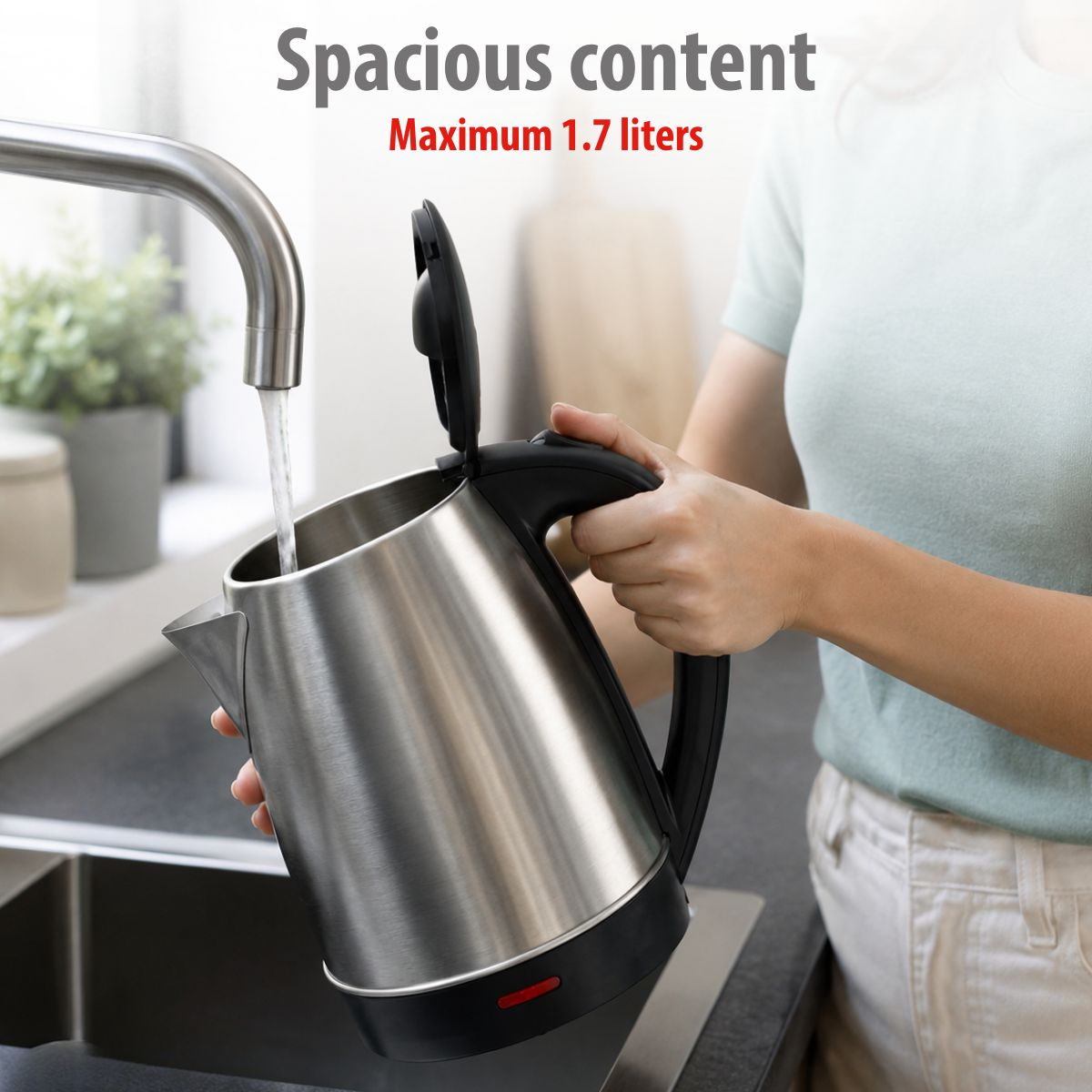 A person fills a stainless steel electric kettle with water from a kitchen faucet.