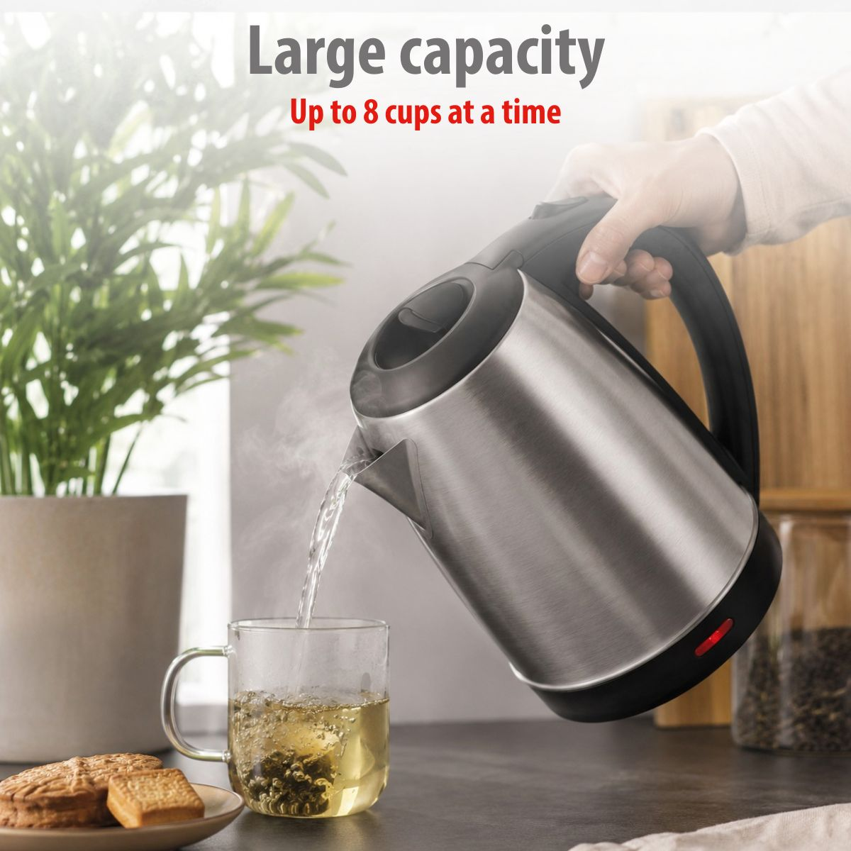Stainless steel kettle pours hot water into a tea mug with biscuits nearby.