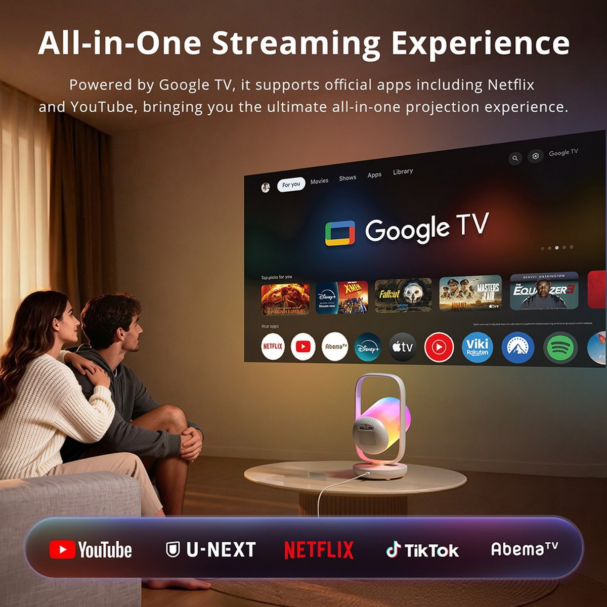 Ein Paar sitzt auf dem Sofa und schaut auf eine wandprojizierte Google TV-Oberfläche, beleuchtet durch einen Projektor.
