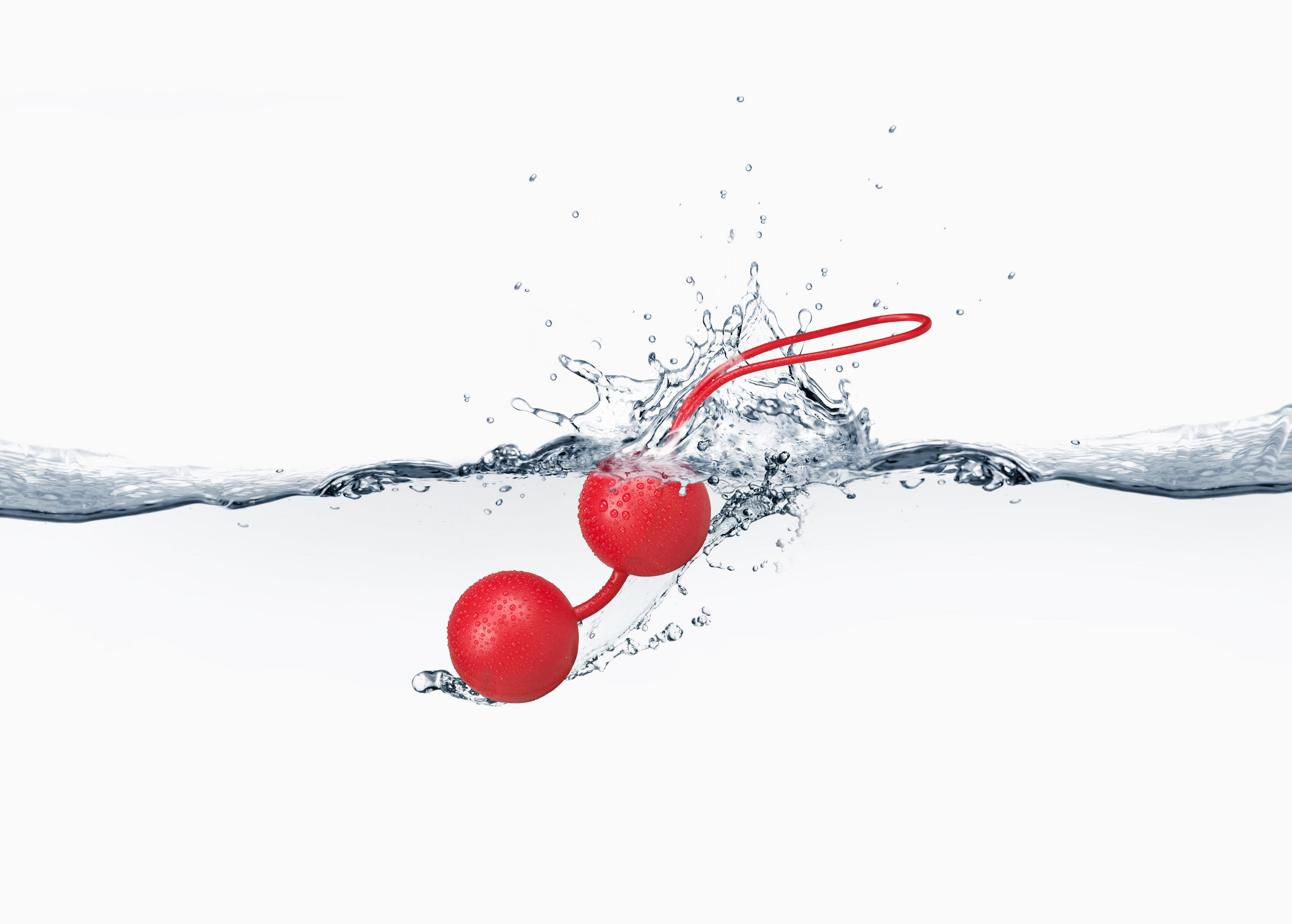 Rote Liebeskugeln tauchen in Wasser ein und erzeugen Wasserspritzer.