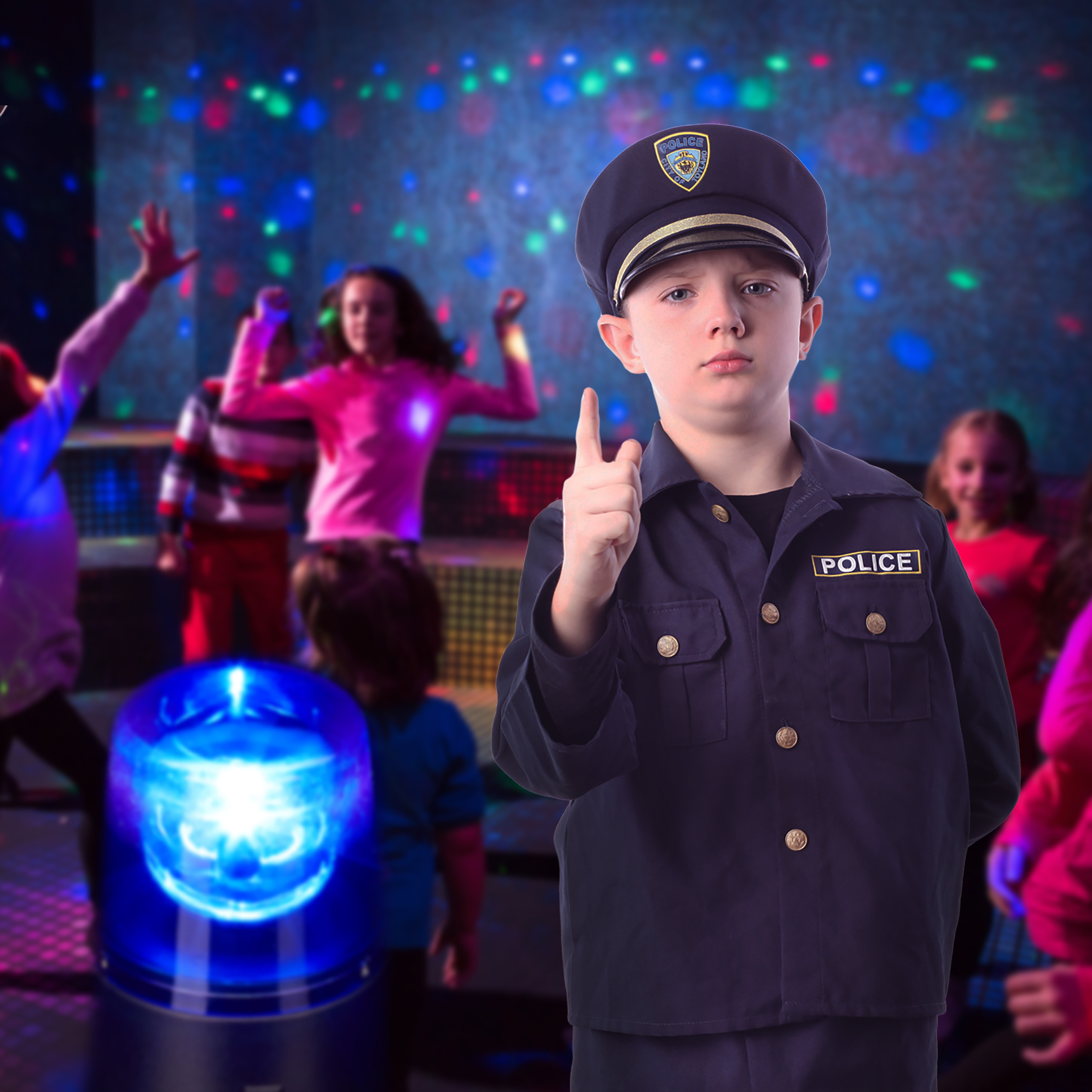 Ein Junge im Polizeikostüm hebt den Finger, mit blauem Licht im Vordergrund und tanzenden Kindern im Hintergrund.