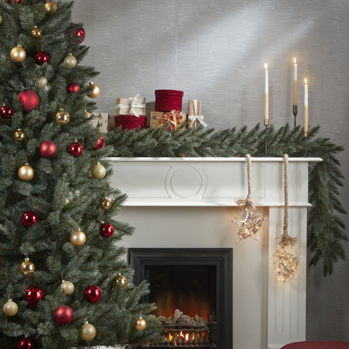 Un sapin de Noël décoré, une cheminée avec guirlande, cadeaux et bougies allumées.