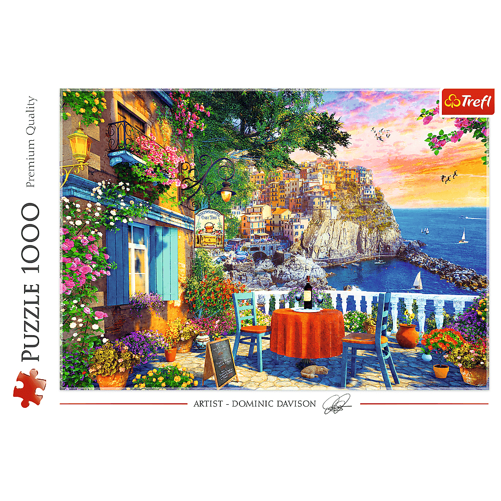 Ein mediterraner Balkon mit gedecktem Tisch overlooking a coastal town at sunset with boats on the sea.