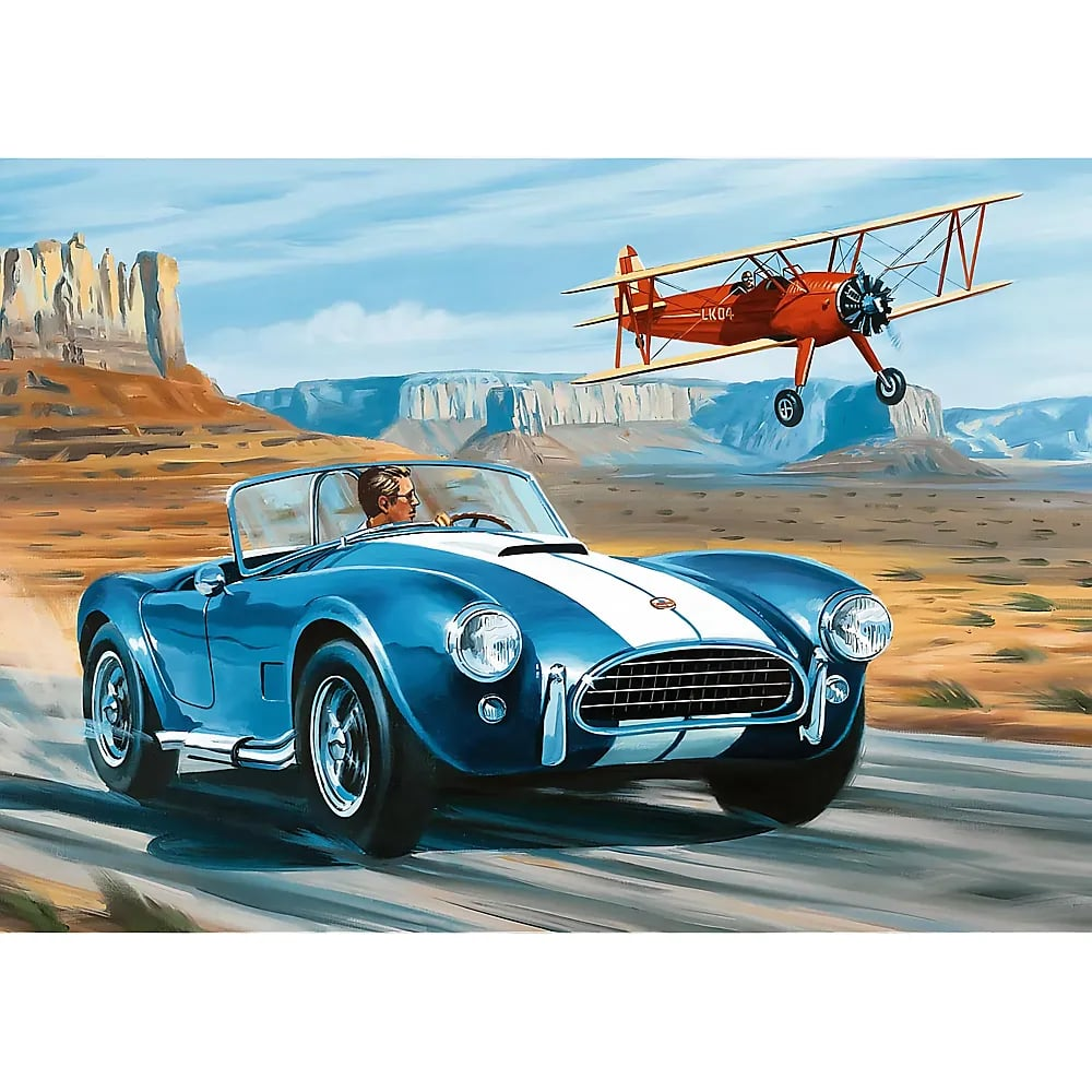 Ein Mann fährt ein blaues Sportauto auf einer Straße, während ein rotes Doppeldeckerflugzeug in einer Wüste fliegt.