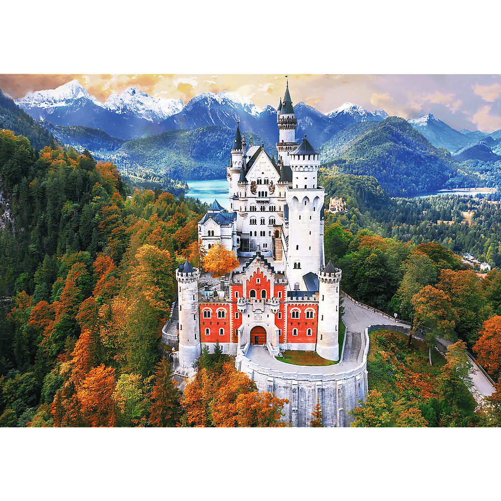Das Schloss Neuschwanstein steht inmitten von Herbstwäldern mit schneebedeckten Bergen im Hintergrund.