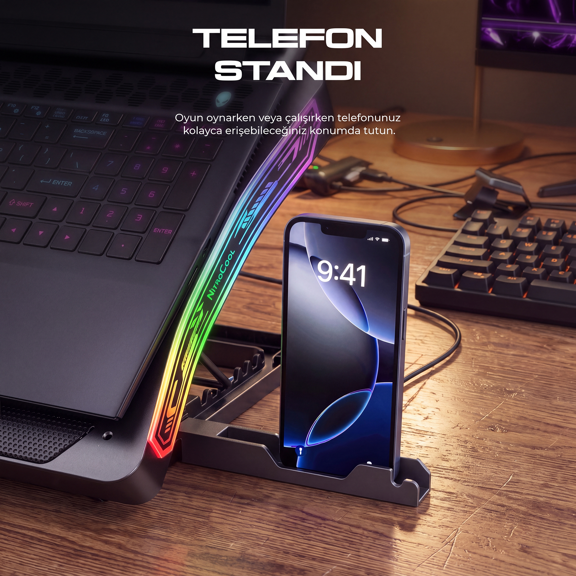 RGB aydınlatmalı oyun dizüstü bilgisayarının yanında masaüstü standında bir akıllı telefon.
