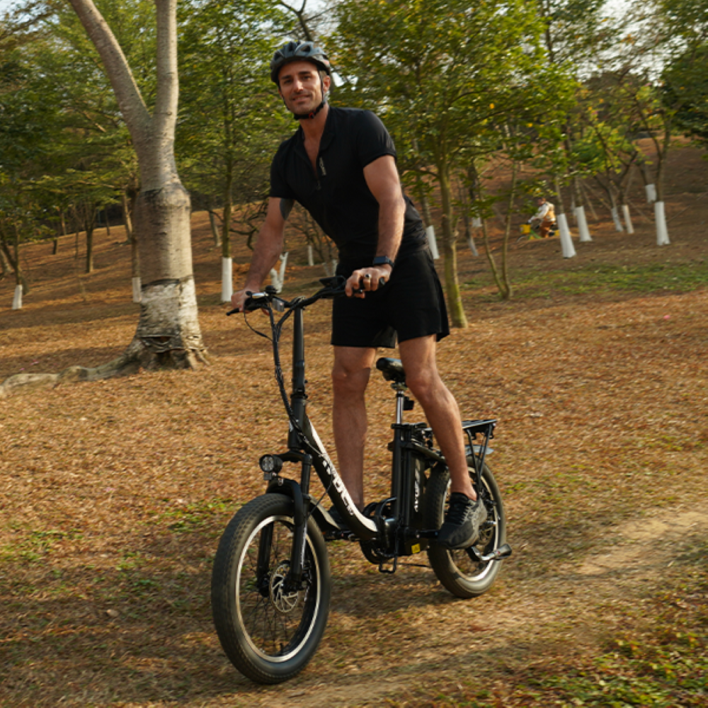 Un uomo con casco guida una e-bike in un parco, guardando verso la camera.