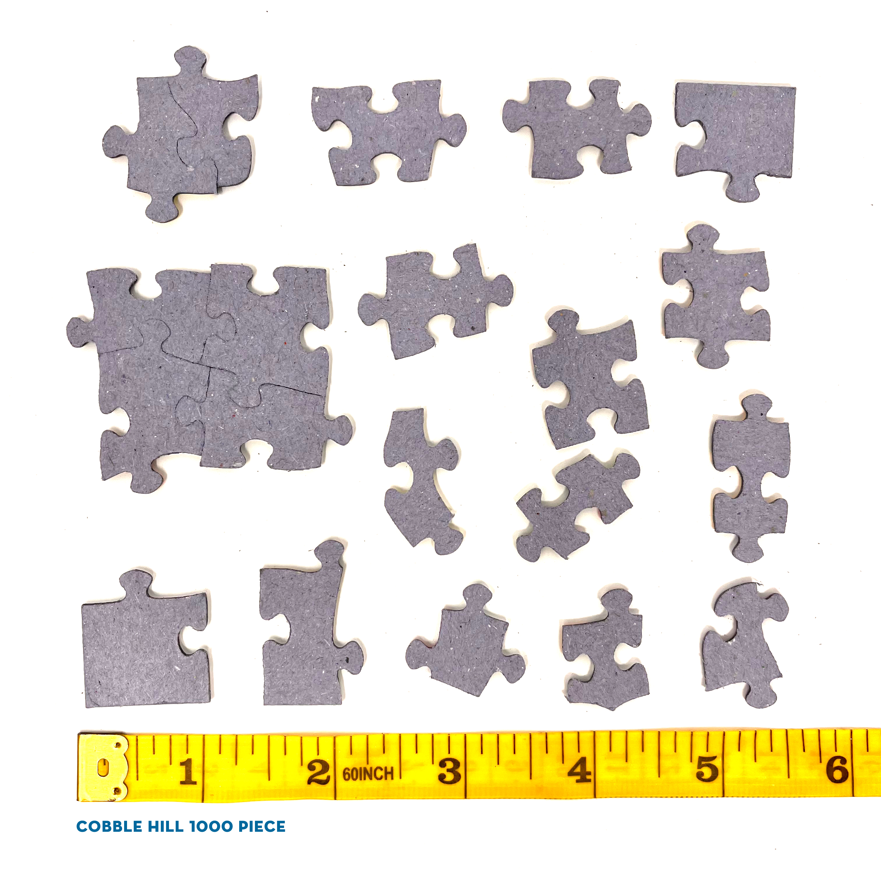Graue Puzzleteile verschiedener Formen vor weißem Hintergrund mit einem gelben Maßstab unten.