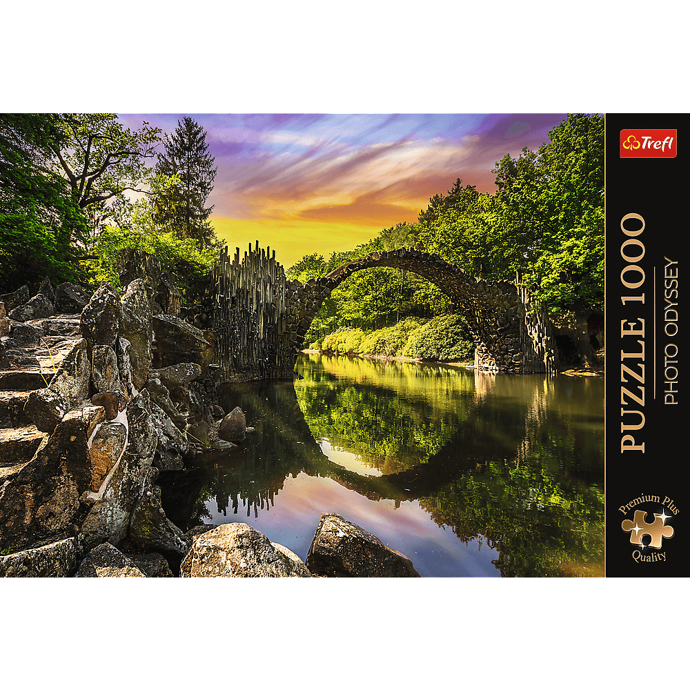 Eine Bogenbrücke spiegelt sich im Fluss bei Sonnenuntergang, umgeben von Wald.