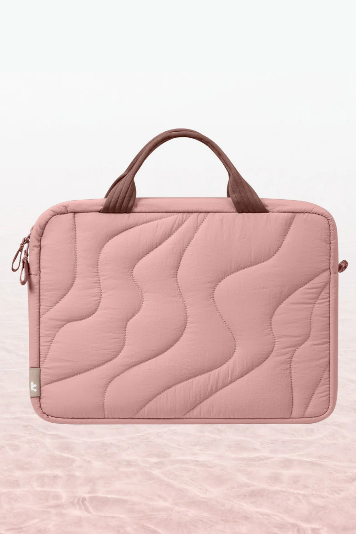 Kahverengi kulplu ve fermuarlı pembe kapitone laptop çantası, nötr arka planda.
