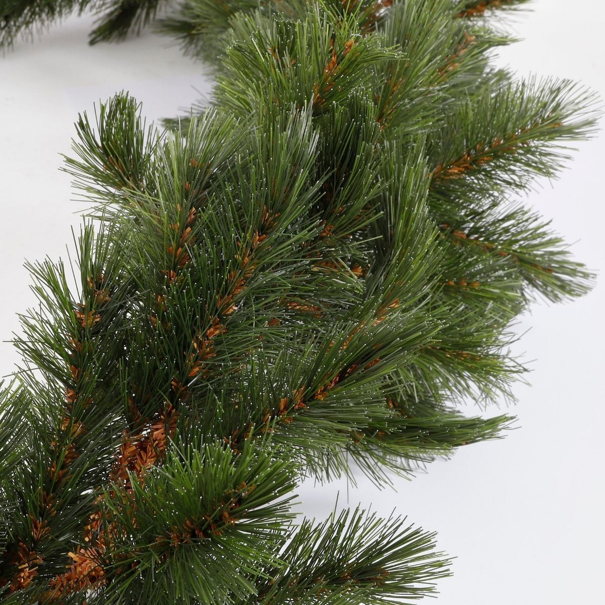 Une guirlande de pin artificielle verte est présentée sur fond blanc.