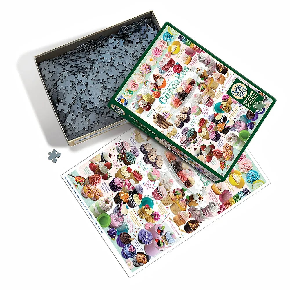 Eine offene Puzzle-Schachtel mit Cupcakes, verstreuten Teilen und einem Poster.