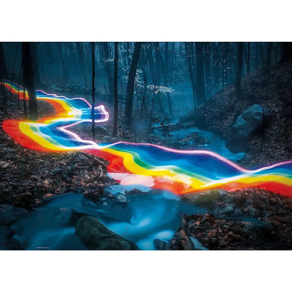 Eine lange, wellenförmige Lichtspur in Regenbogenfarben schlängelt sich durch ein dunkles, nebliges Waldgebiet.