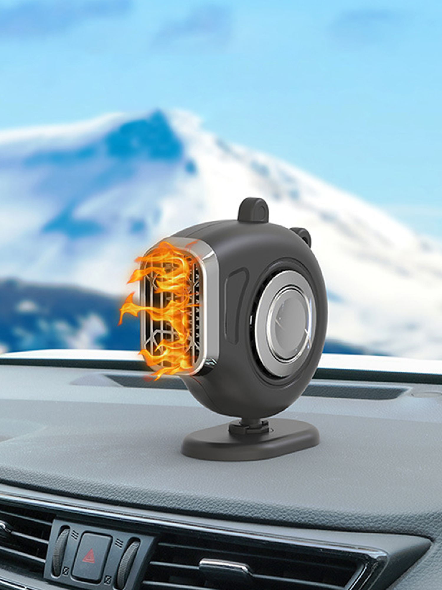 Ein schwarzer Autoluftheizer auf dem Armaturenbrett vor einer verschneiten Berglandschaft.