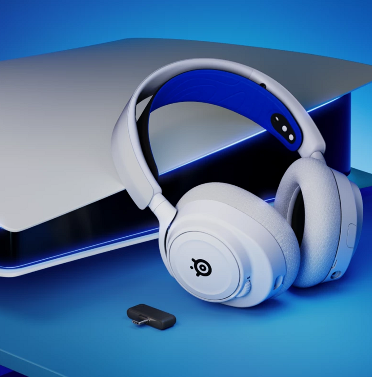 Weiß-blaue Gaming-Kopfhörer und ein USB-C-Adapter vor einer Playstation 5 auf blauem Hintergrund.