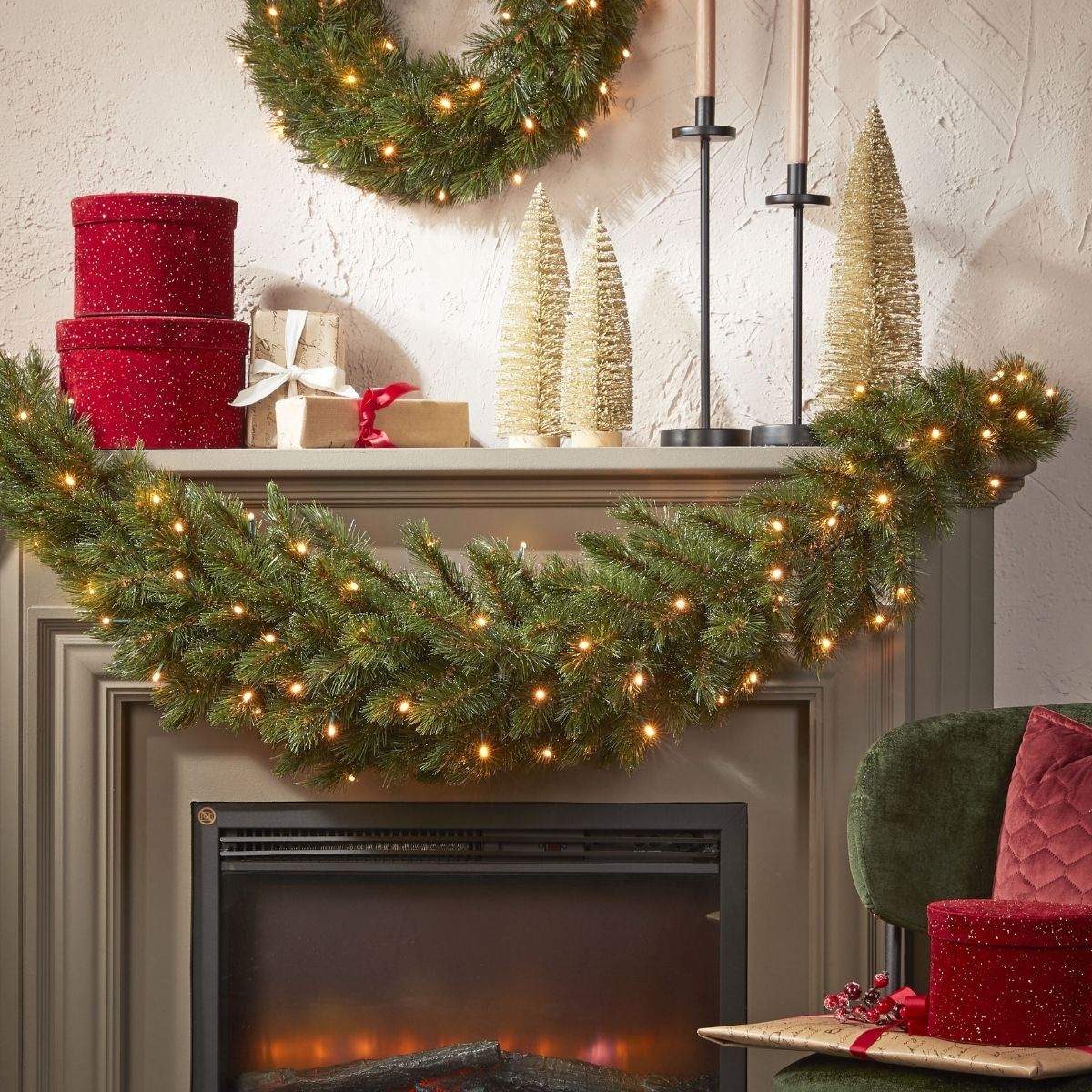 Kamin mit beleuchteter Girlande, Kranz, roten Geschenkboxen und goldenen Tannenbäumen.